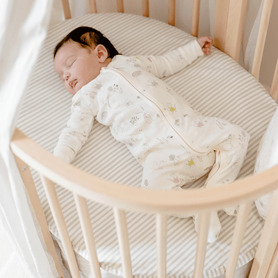 Baby in a crib sleeping on Stokke's Sleepi V3 Mini Fitted Sheet By Pehr in -- Color_Stripes Away Pebbles