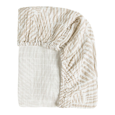 Back corner view of Babyletto's All-Stages Midi Crib Sheet In GOTS Certified Organic Muslin Cotton in -- Color_Oat Stripe