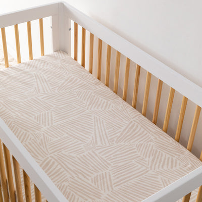 An empty crib equipped with the Babyletto's Crib Sheet in GOTS Certified Organic Muslin Cotton in -- Color_Oat Stripe
