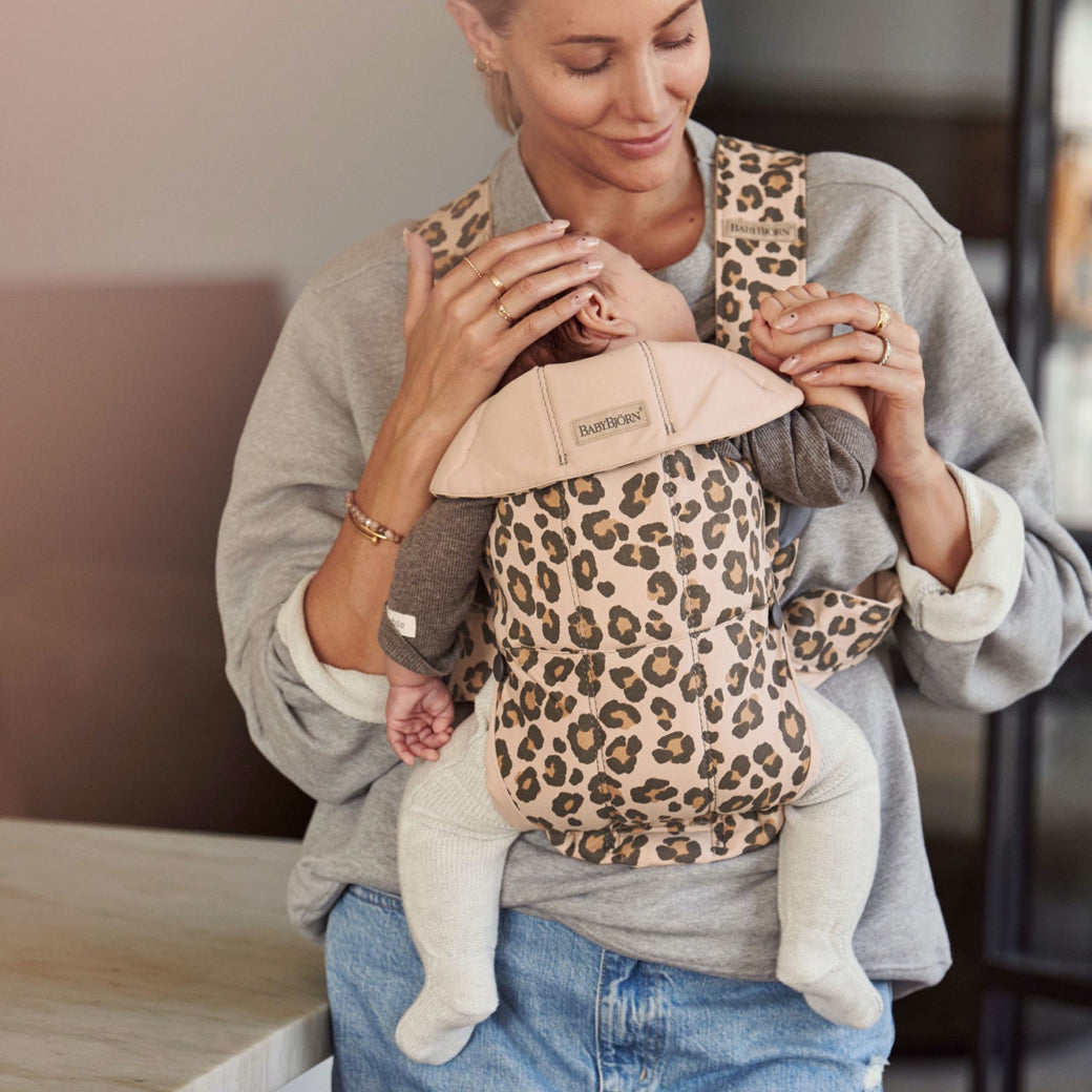 Mom carrying baby in BABYBJÖRN Baby Carrier Mini in -- Color_Beige Leopard Cotton