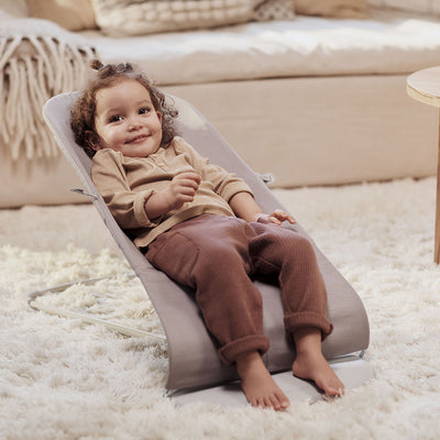 Smiling toddler in BABYBJÖRN Bouncer Bliss in -- Color_Sand Gray Woven, Classic Quilt