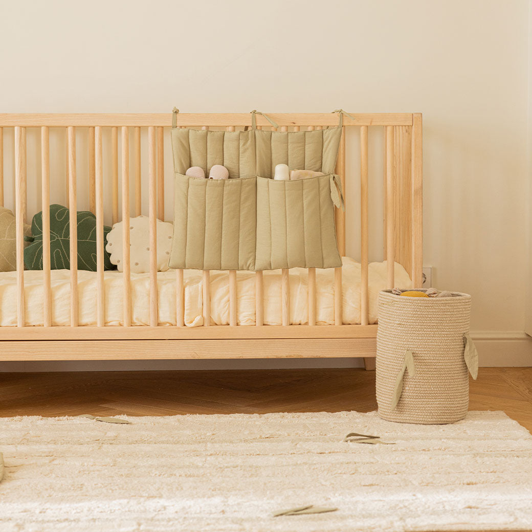 Lorena Canals Bamboo Cane Basket next to a crib with Benjamin pocket hangers 