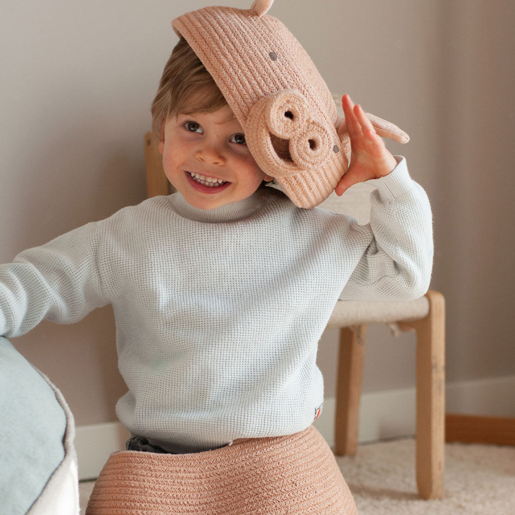 A child playing with the Lorena Canals Peggy the Pig Basket with the top on his head