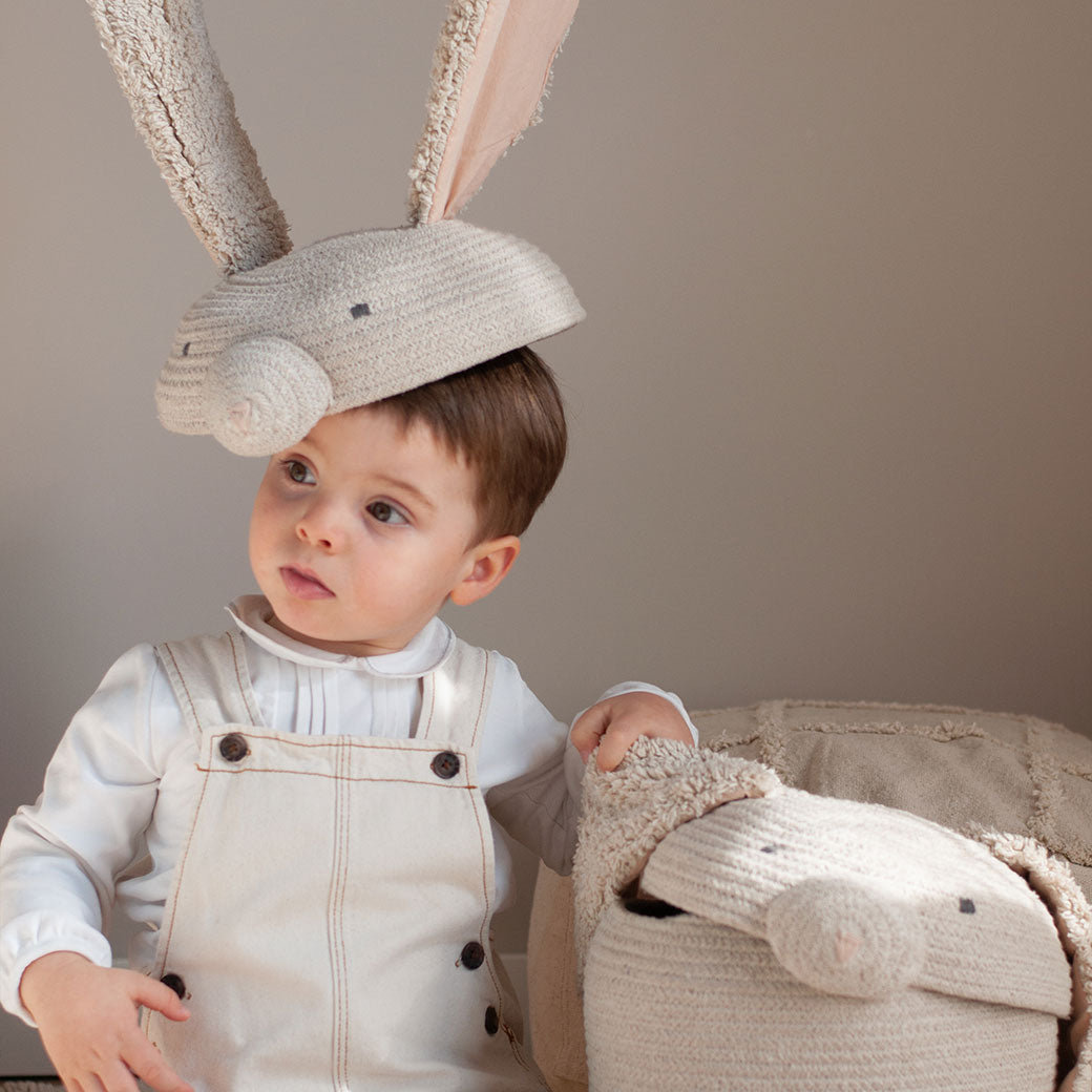 A child sitting next to Lorena Canals Rita the Rabbit Basket with the top on his head