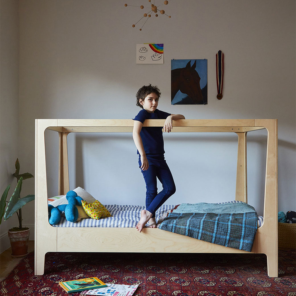 Lifestyle view of Oeuf Perch Nest Bed with a child standing on the middle mattress