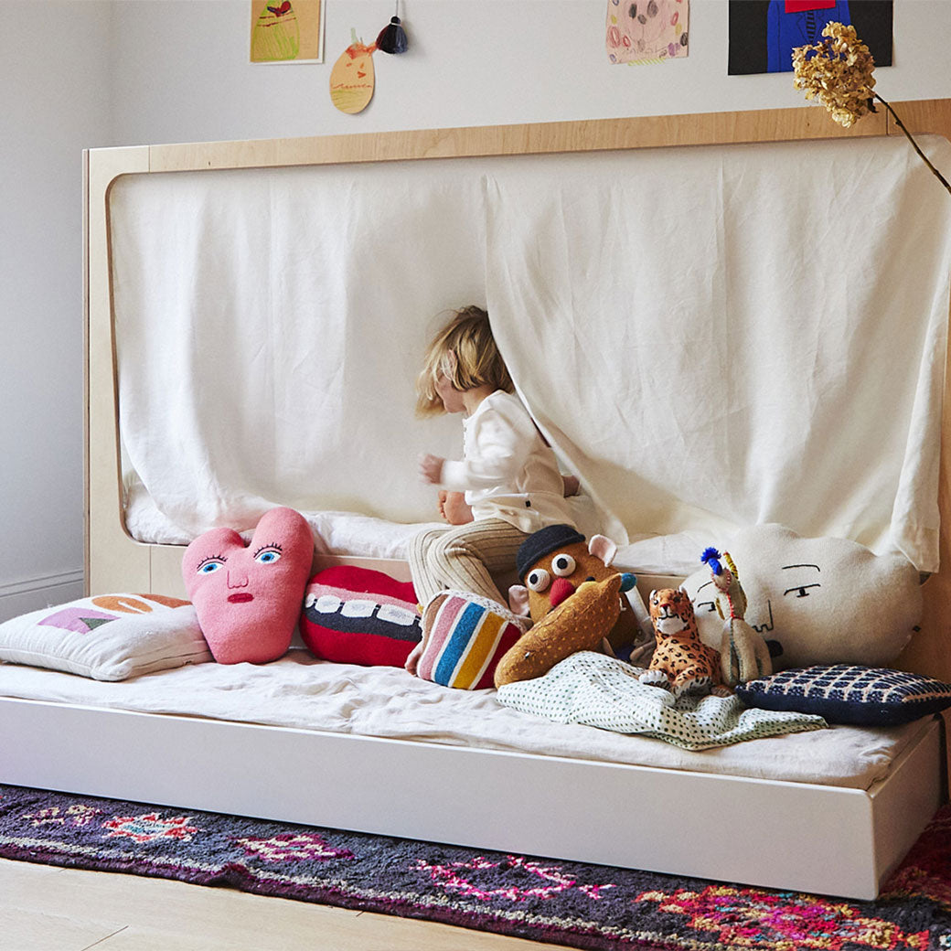 Lifestyle view of Oeuf Perch Nest Bed with the middle and lower mattress  and a child sitting on it 