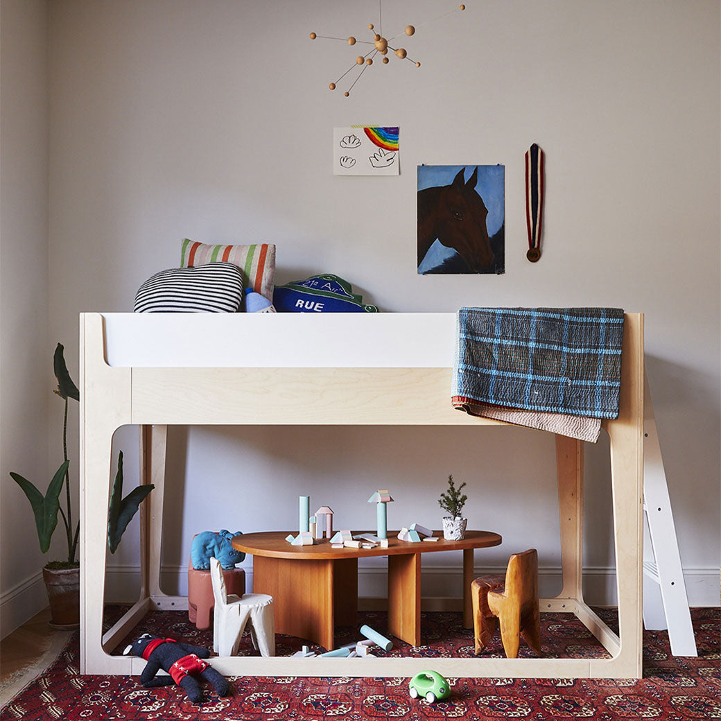 Lifestyle view of Oeuf Perch Nest Bed with a mattress on top and a play table bellow it 
