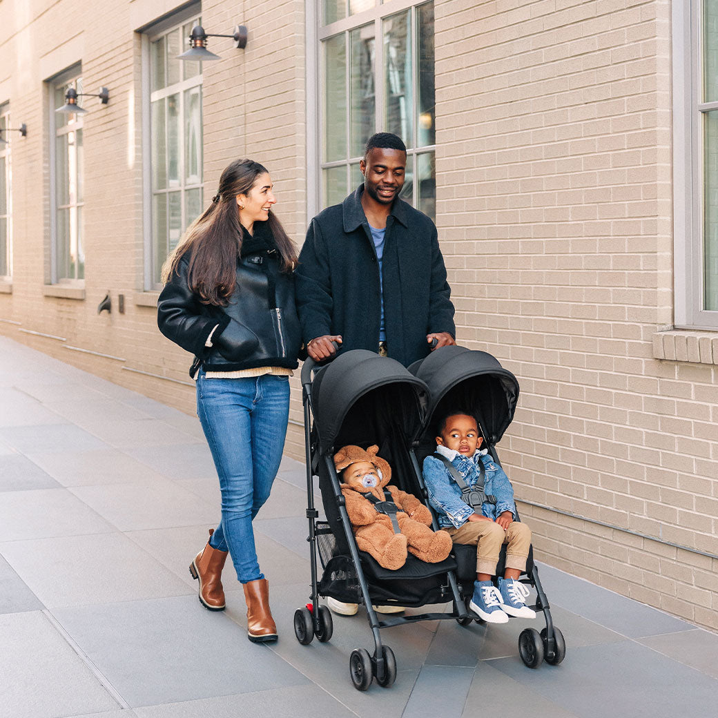 Mother and father walking and pushing their kids in the UPPAbaby G Link V2 Stroller in --Color_Jake