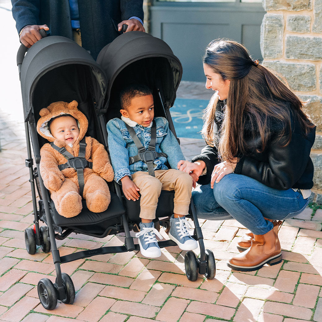Mother crouched next to two children in UPPAbaby G Link V2 Stroller in --Color_Jake