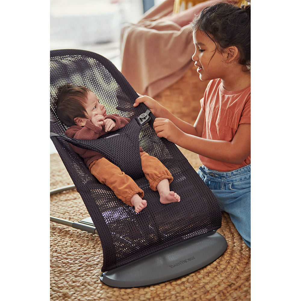 Baby looking at sister in BABYBJÖRN Bouncer Bliss in -- Color_Anthracite (Slate Gray) Mesh