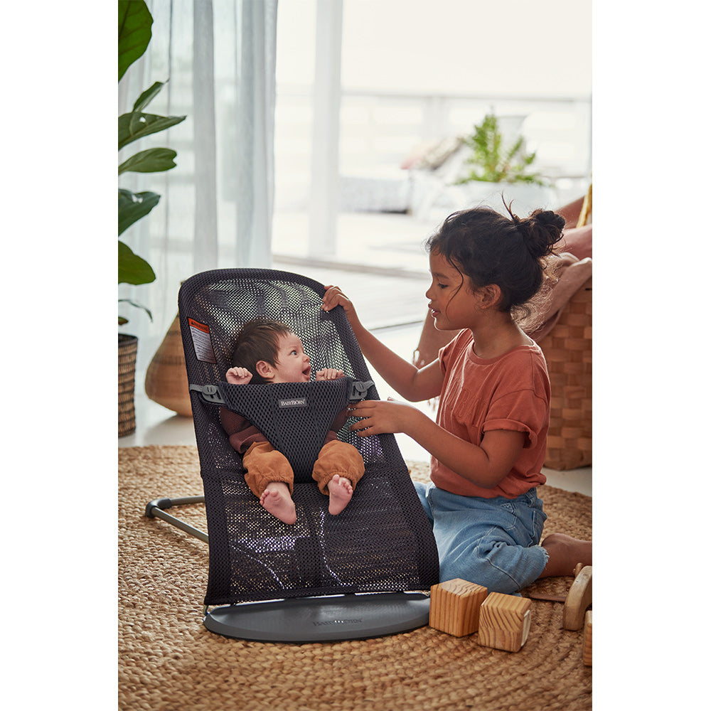 Front view of baby sitting in BABYBJÖRN Bouncer Bliss next to sister in -- Color_Anthracite (Slate Gray) Mesh