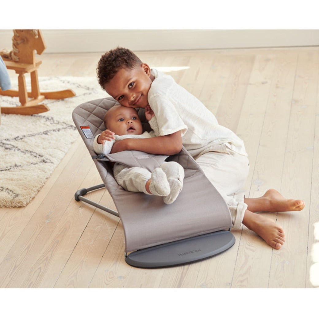 Baby in BABYBJÖRN Bouncer Bliss next to brother in -- Color_Sand Gray Woven, Classic Quilt