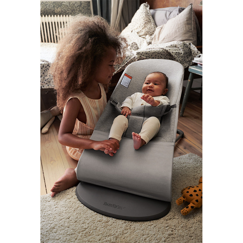Toddler holding little foot of a baby sitting in the BABYBJÖRN Bouncer Bliss in -- Color_Light Gray 3D Jersey