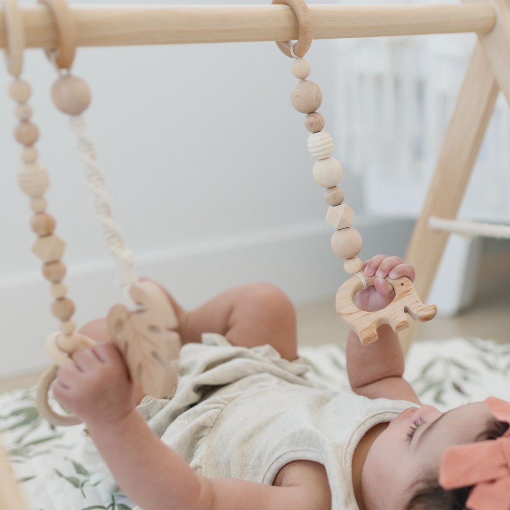 Baby playing with Poppyseed Play Wood Baby Gym + Toys in -- Color_White _ Macrame
