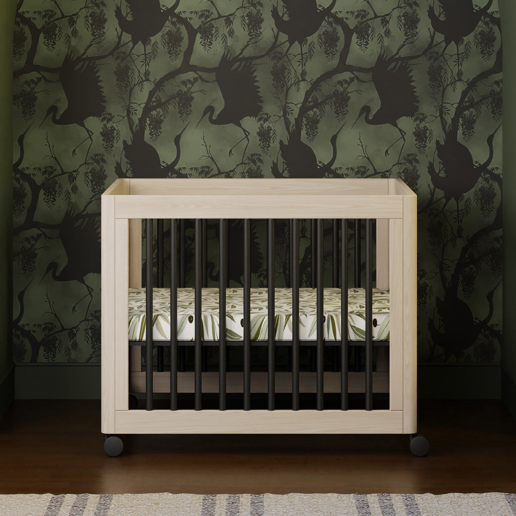 Front view of Babyletto's Yuzu 8-In-1 Convertible Crib With All Stages Conversion Kits as midi crib in green-wallpaper room  in -- Color_Washed Natural / Black