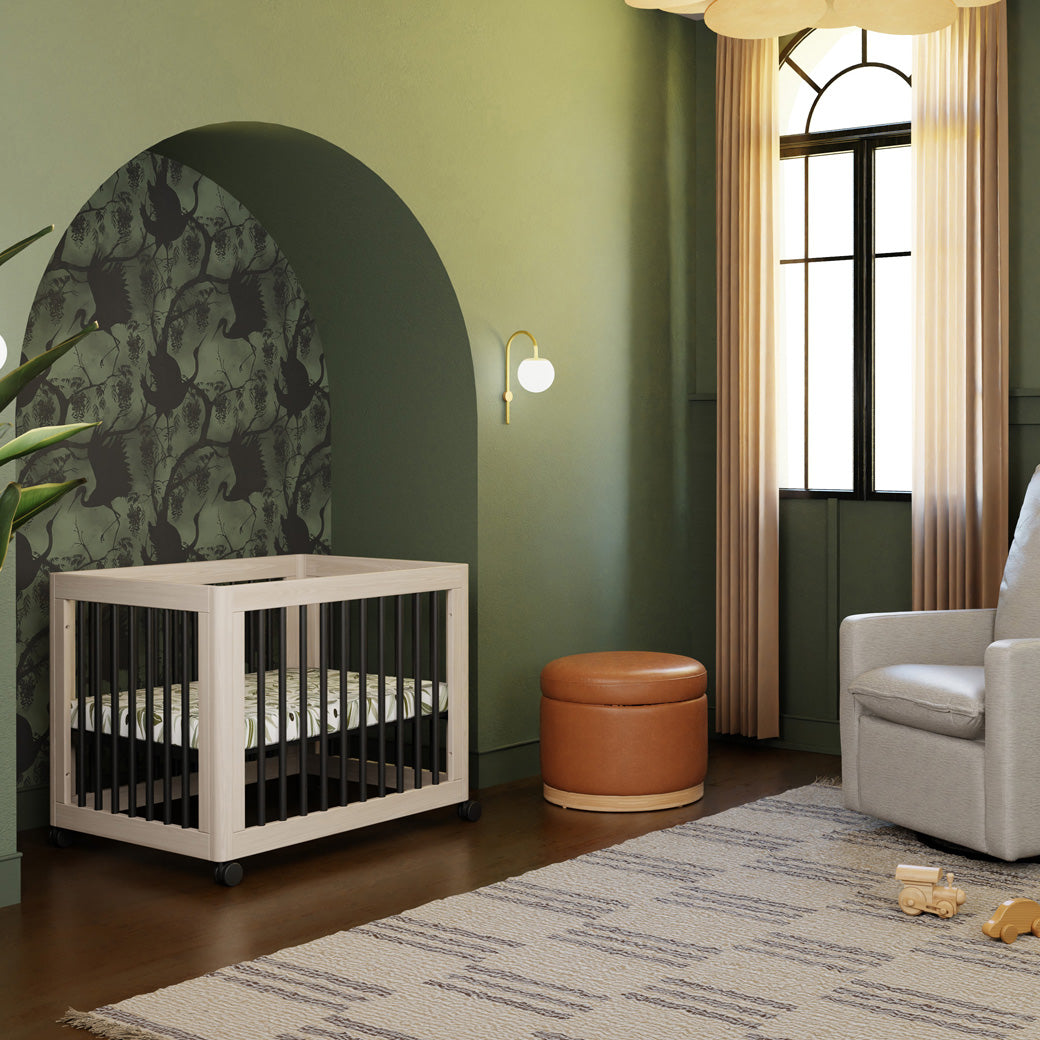 Babyletto's Yuzu 8-In-1 Convertible Crib With All Stages Conversion Kits next to ottoman and recliner  in -- Color_Washed Natural / Black