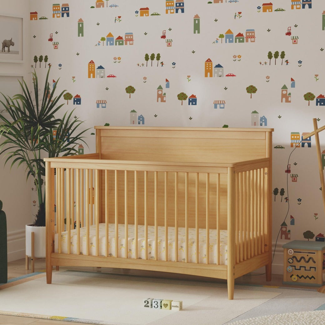 DaVinci Margot 3-in-1 Convertible Crib next to plant in -- Color_Honey