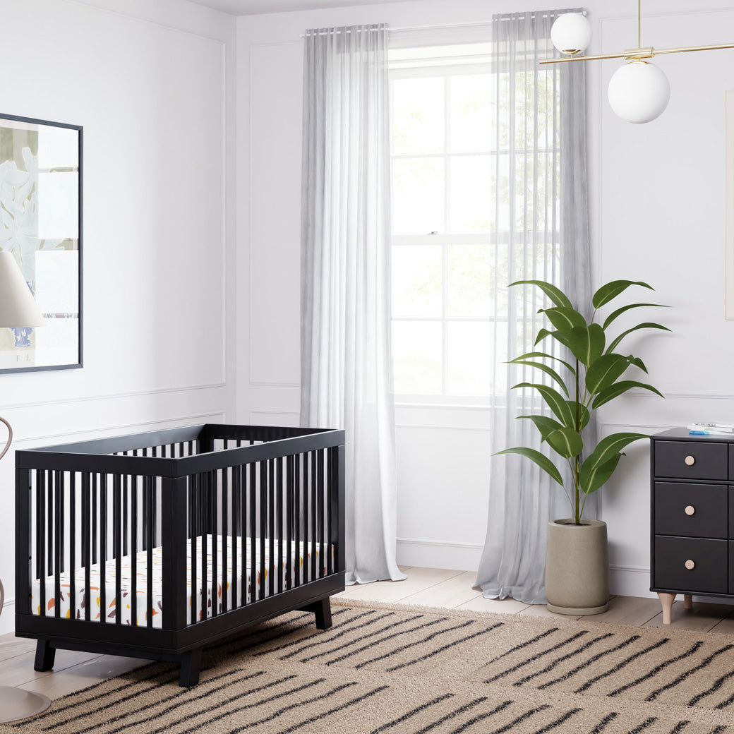 Babyletto Hudson 3-in-1 Crib next to a window and dresser  in -- Color_Black