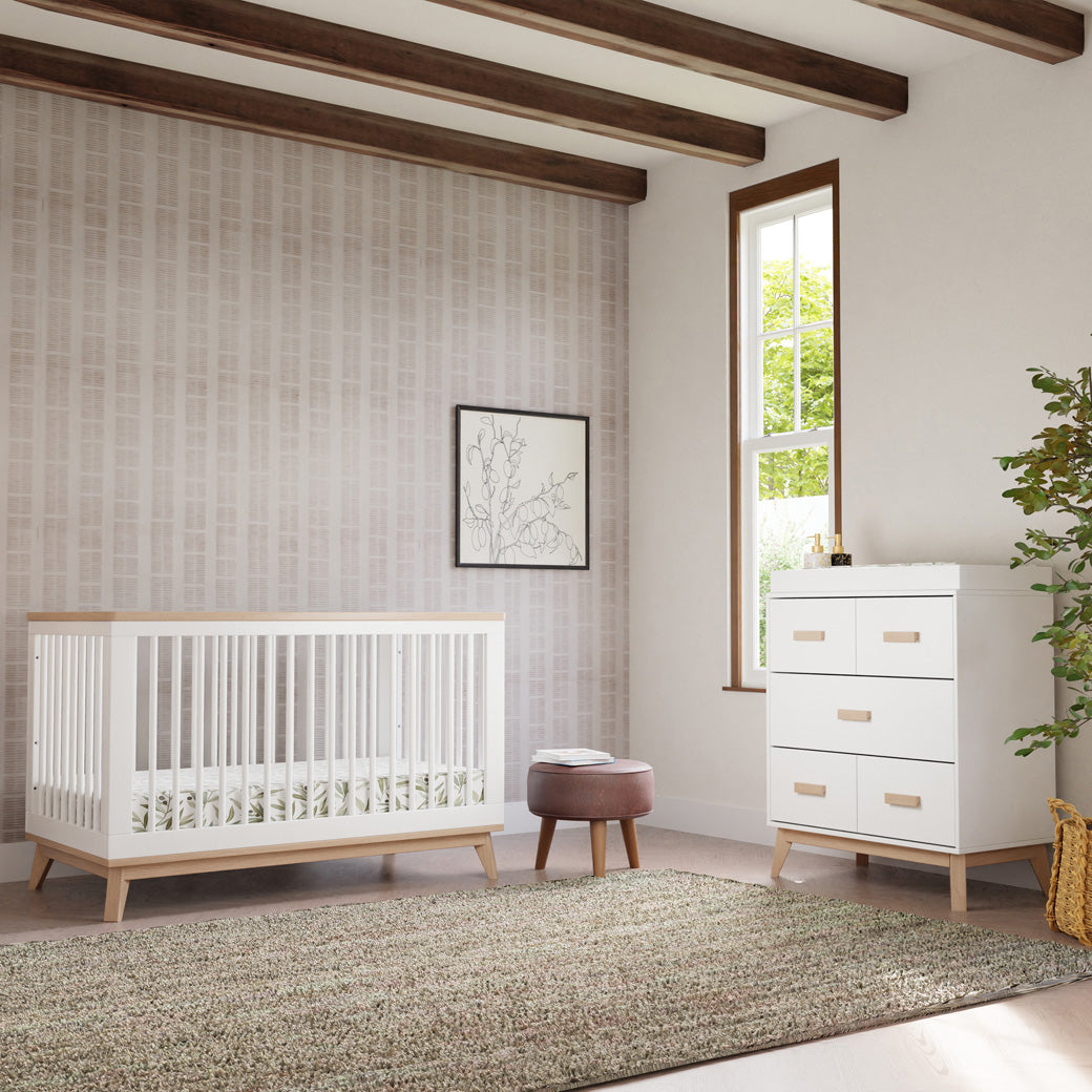 Babyletto's Scoot 3-in-1 Convertible Crib + Toddler Rail next to a dresser and stool  in -- Color_Washed Natural/White