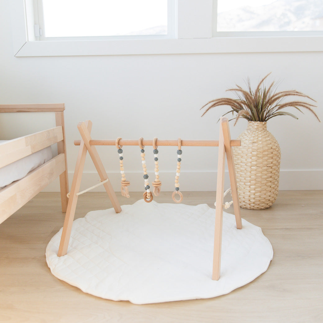 Poppyseed Play Wood Baby Gym + Toys on a mat in -- Color_Natural _ Gray