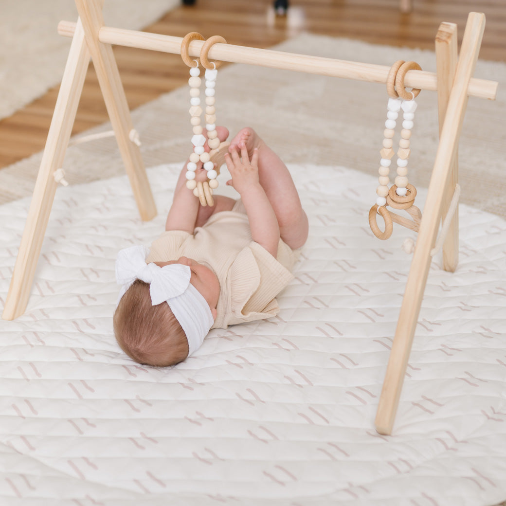Baby playing with Poppyseed Play Wood Baby Gym + Toys in -- Color_Natural _ White