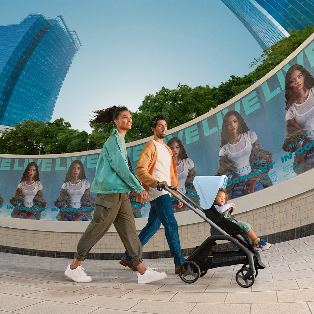 Mom and dad pushing their child in the Bugaboo Dragonfly Stroller in -- Color_Skyline Blue