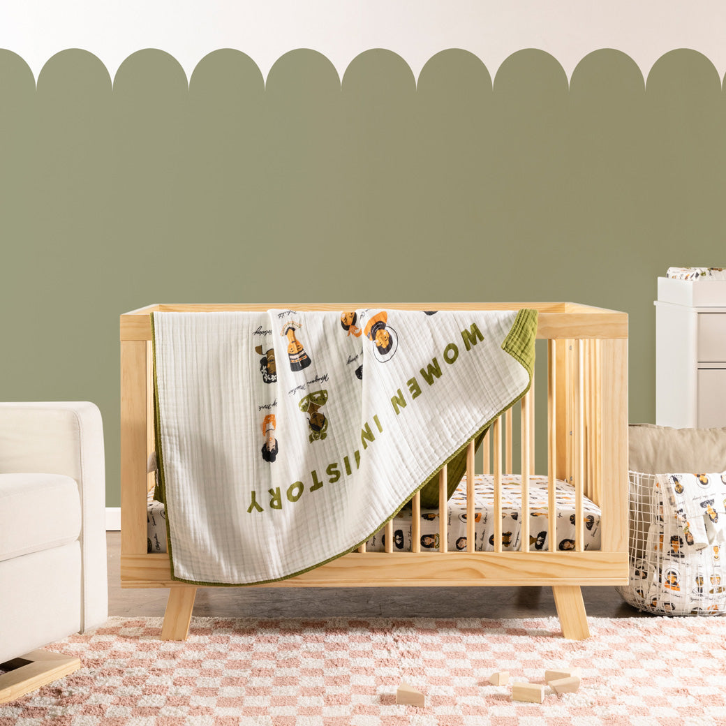 Babyletto's Quilt In 3-Layer GOTS Certified Organic Muslin Cotton on a crib  next to a recliner  in -- Color_Women In History