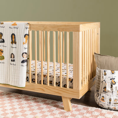 Babyletto's Quilt In 3-Layer GOTS Certified Organic Muslin Cotton on a crib next to a basket in -- Color_Women In History