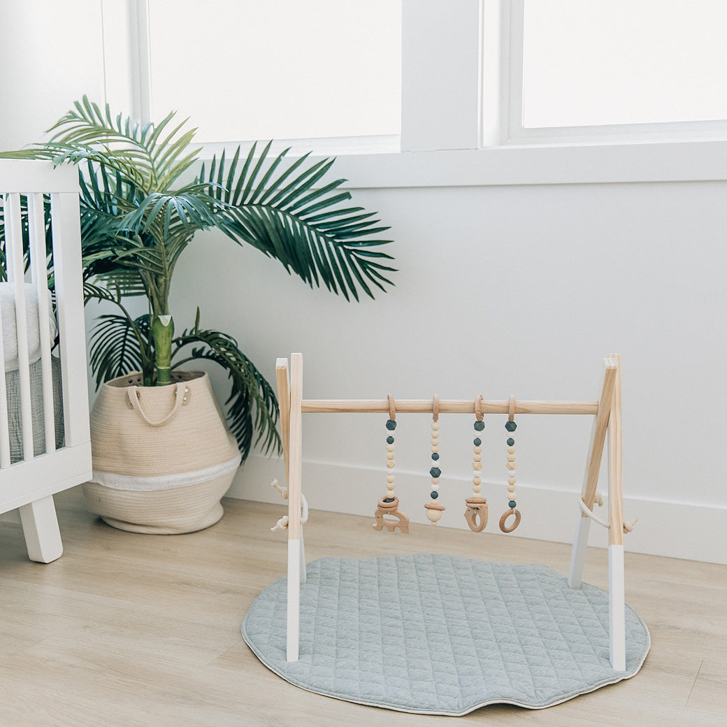 Poppyseed Play Wood Baby Gym + Toys on a gray mat in -- Color_White _ Gray