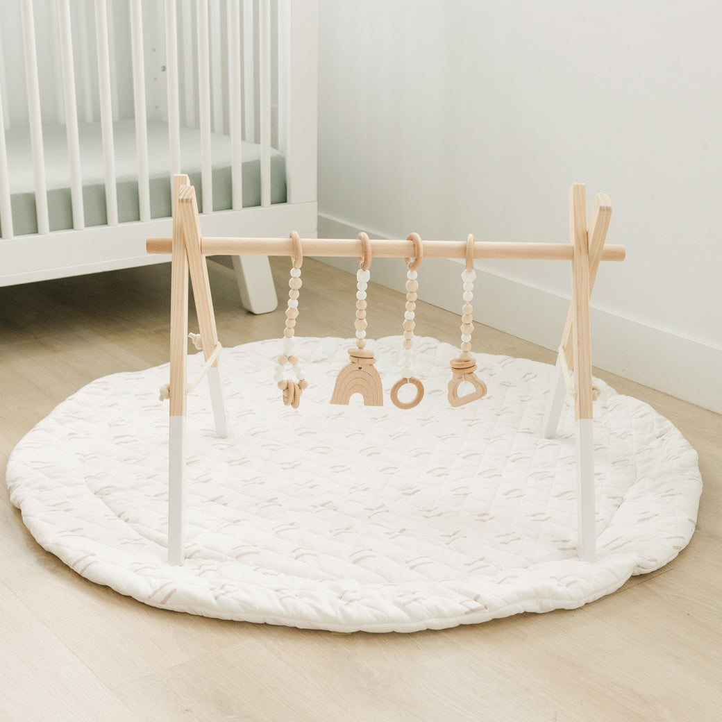 Poppyseed Play Wood Baby Gym + Toys on a white mat in -- Color_White _ White