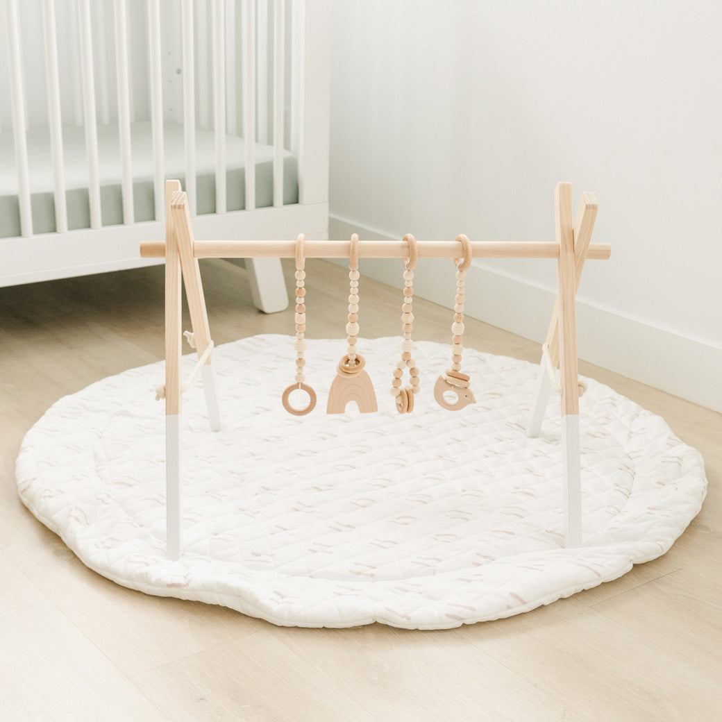 Poppyseed Play Wood Baby Gym + Toys on a mat in -- Color_White _ Wood