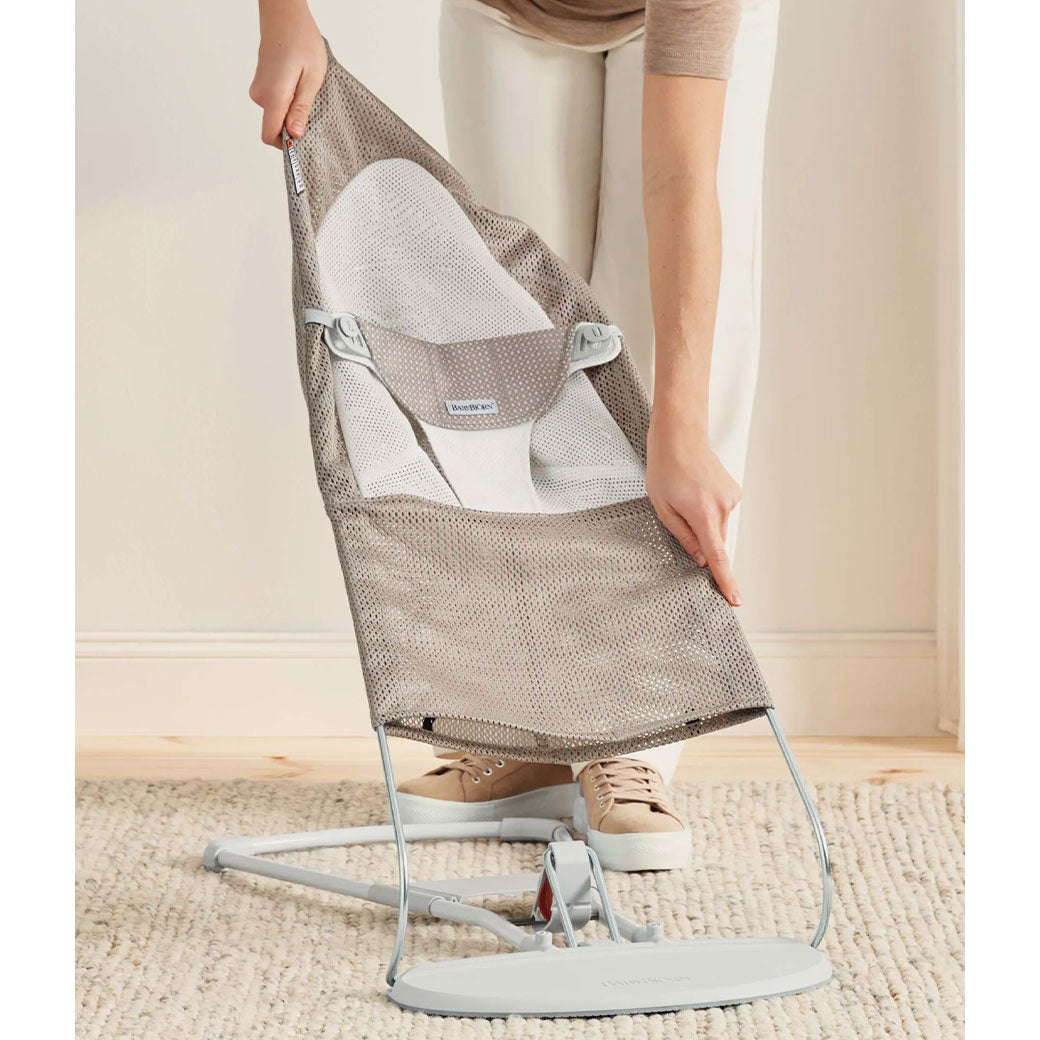 Mom taking off the fabric from the BABYBJÖRN Bouncer Balance Soft in -- Color_Grey Beige/White Mesh