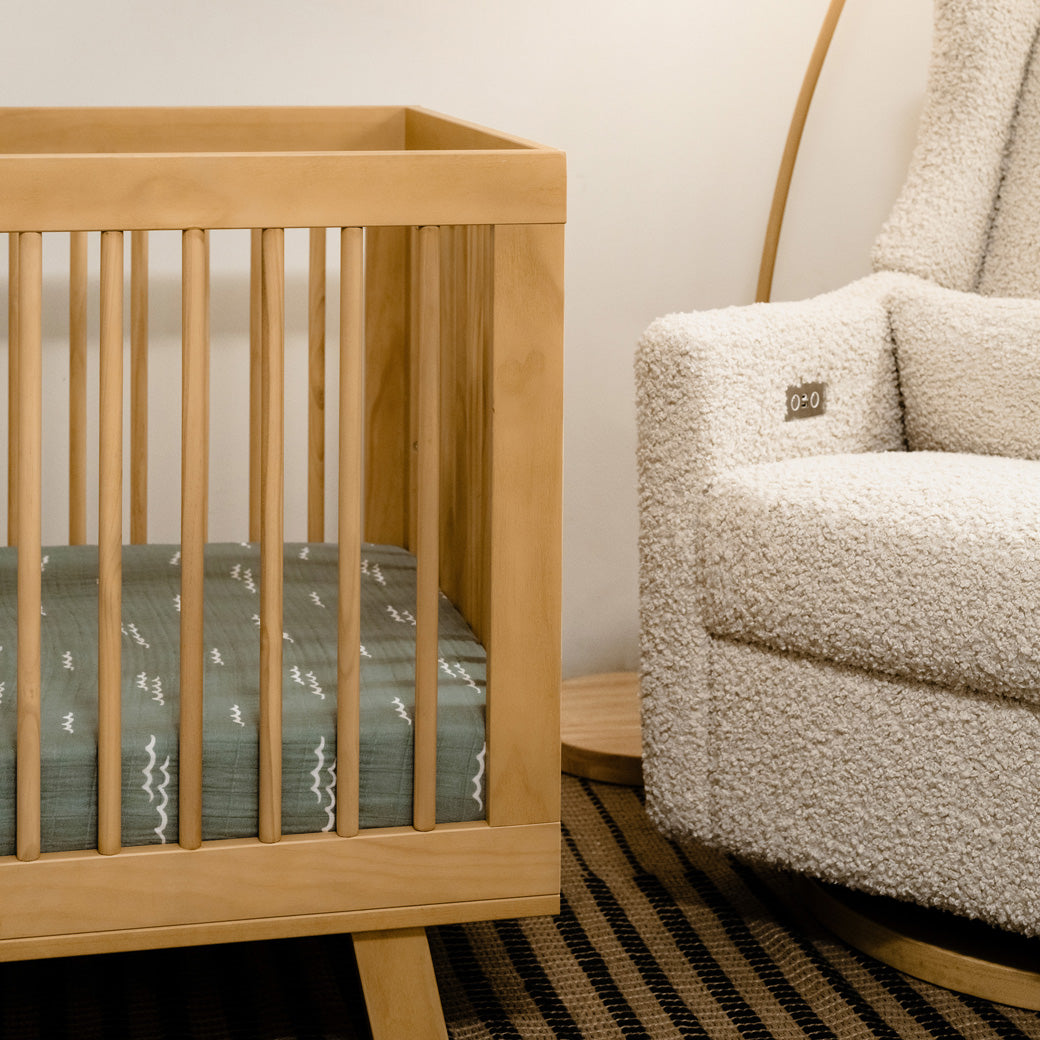 Closeup of Babyletto Hudson 3-in-1 Convertible Crib And Toddler Rail next to recliner in -- Color_Honey
