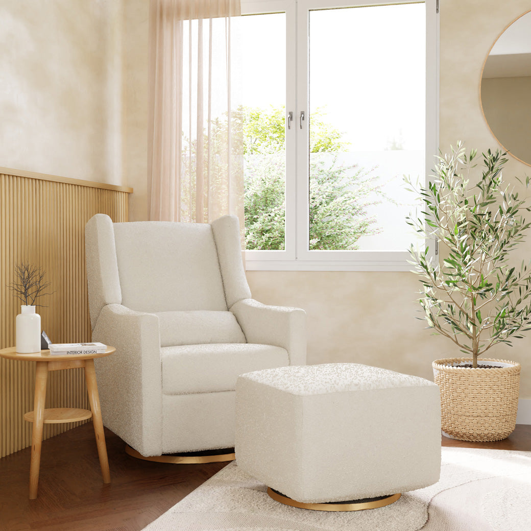 Babyletto Kiwi Glider Recliner next to an ottoman, window, and plant  in -- Color_Ivory Boucle with Gold Base