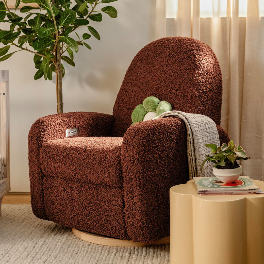 The Babyletto Nami Glider Recliner next to a coffee table and plant in -- Color_Rouge Teddy Loop with Light Wood Base