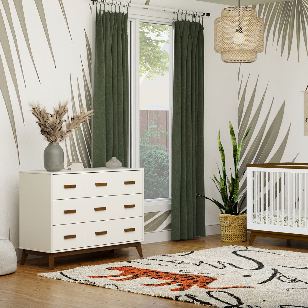 Babyletto Scoot 6-Drawer Dresser next to a window and crib in -- Color_White / Natural Walnut