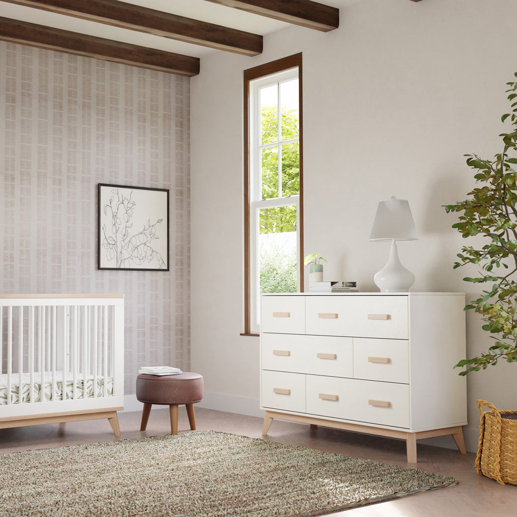 Babyletto Scoot 6-Drawer Dresser next to a window and crib in -- Color_White / Washed Natural