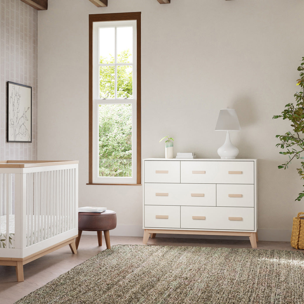 Front view of Babyletto Scoot 6-Drawer Dresser next to window and crib in -- Color_White / Washed Natural