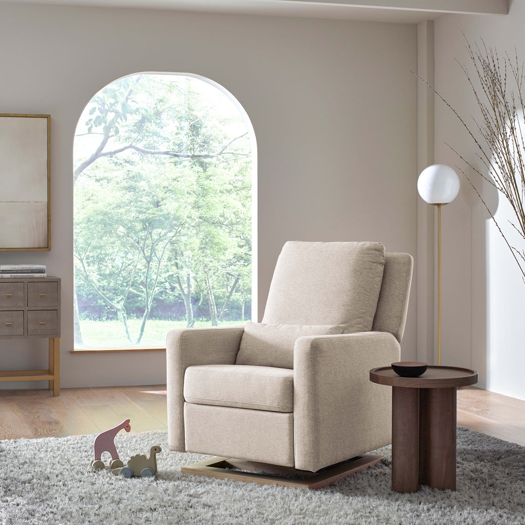 Babyletto Sigi Glider Recliner in front of a window and next to a coffee table  in -- Color_Performance Beach Eco-Weave with Light Wood Base