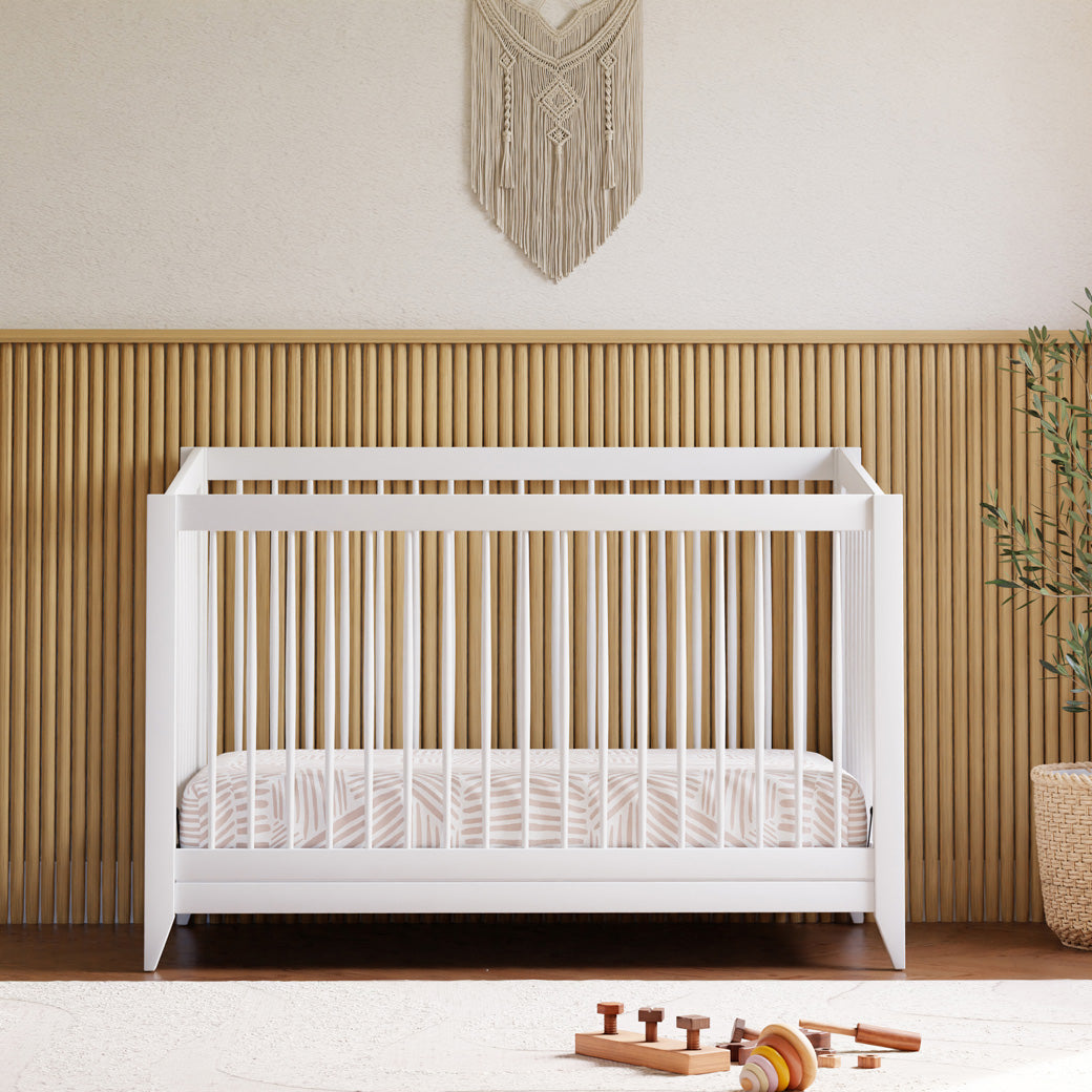 Front view of Babyletto's Sprout 4-in-1 Convertible Crib + Toddler Bed Conversion Kit next to a plant in -- Color_White