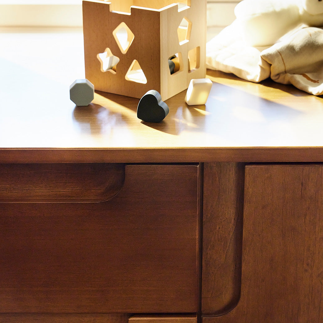 Closeup of Babyletto Yuzu 3-Drawer Changer Dresser with a toy on top in -- Color_Natural Walnut