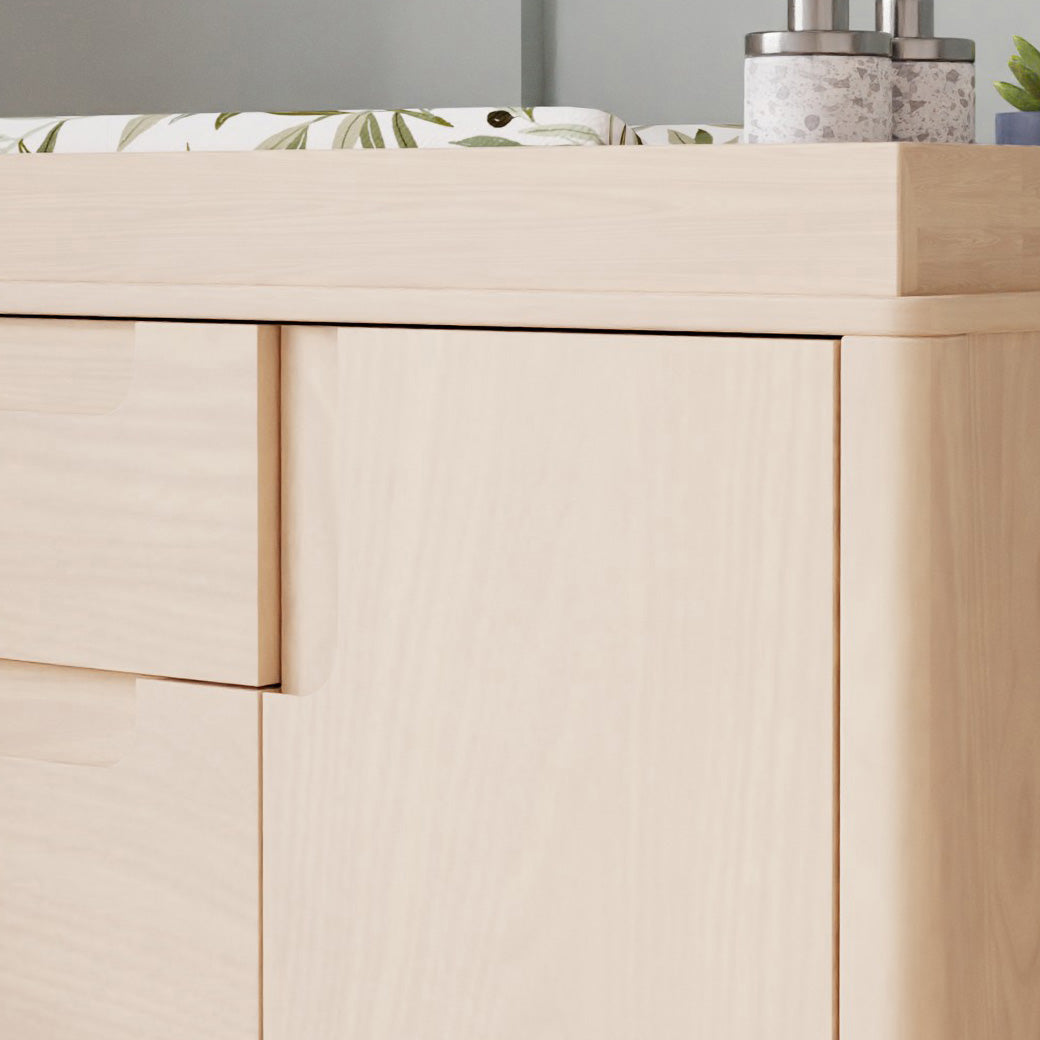 Closeup of Babyletto Yuzu 3-Drawer Changer Dresser with changing tray with products on top  in -- Color_Washed Natural