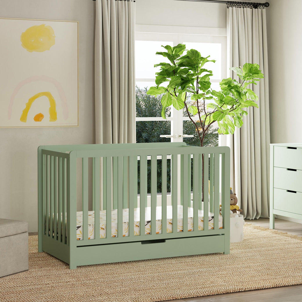 Carter's by DaVinci Colby 4-in-1 Convertible Crib with Trundle Drawer next to a window and dresser  in -- Color_Light Sage