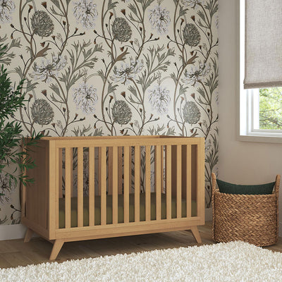 DaVinci Otto 3-in-1 Convertible Crib next to a basket and window in -- Color_Honey _ Wood