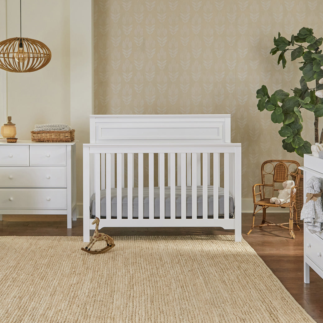 Front view of DaVinci Autumn 4-in-1 Convertible Crib next to a dresser  in -- Color_White