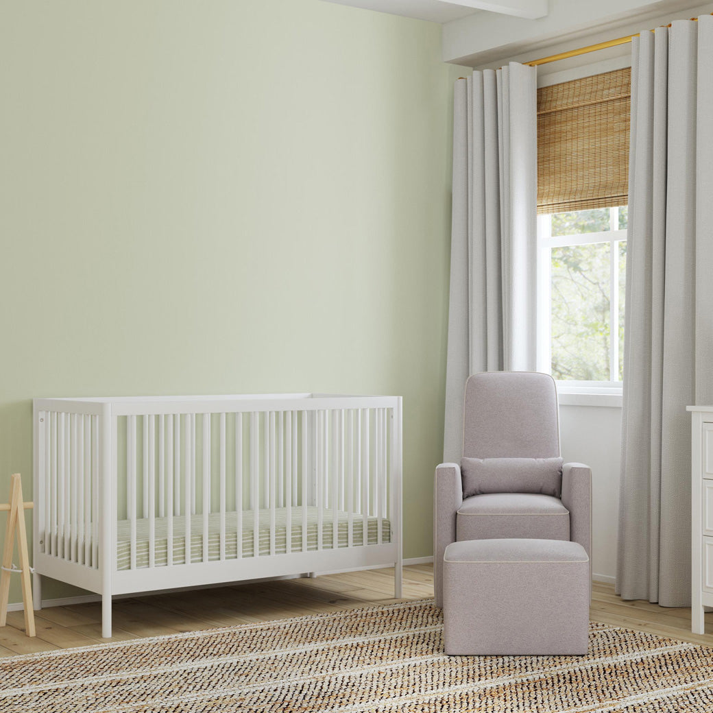 DaVinci Birdie 3-in-1 Convertible Crib next to a recliner and ottoman in -- Color_White