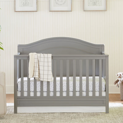 The DaVinci Charlie 4-in-1 Convertible Crib with a blanket over the rail in -- Color_Grey
