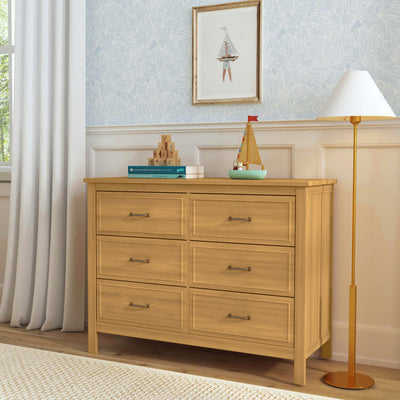 The DaVinci Charlie 6-Drawer Dresser under a picture with items on top of it  in -- Color_Honey