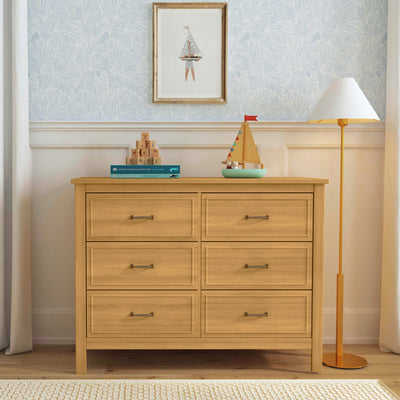 Front view of The DaVinci Charlie 6-Drawer Dresser under a picture with items on top of it  in -- Color_Honey