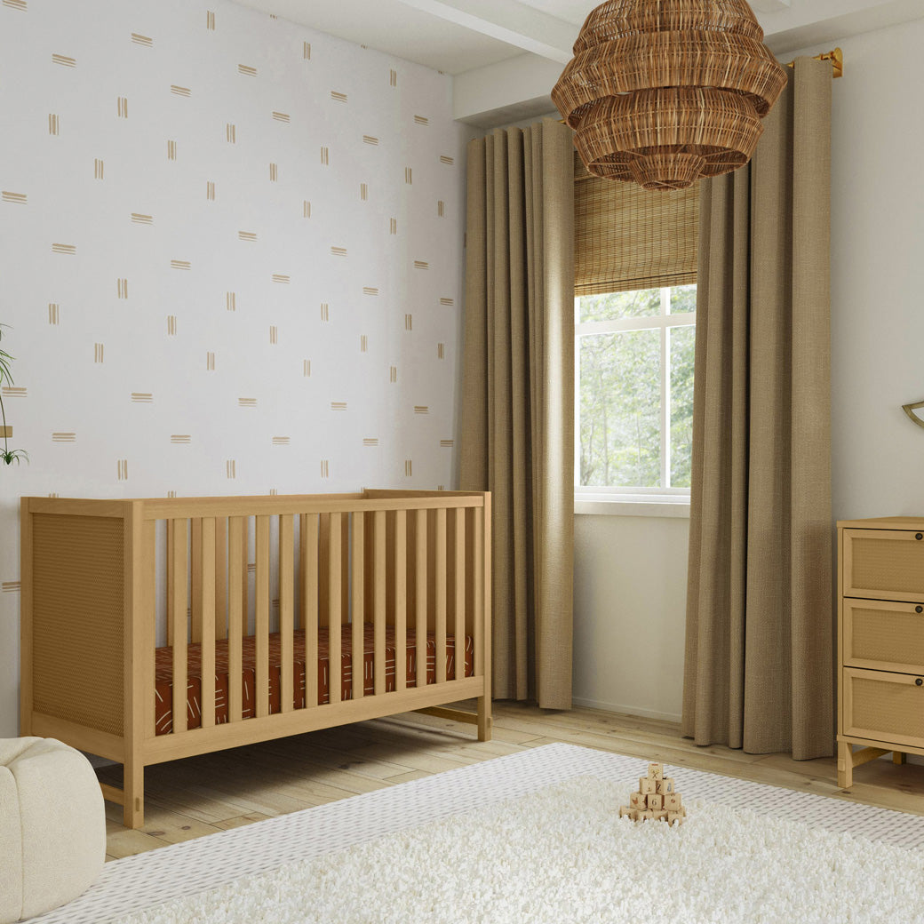 DaVinci Margot 3-in-1 Convertible Crib next to a window and dresser in -- Color_Honey